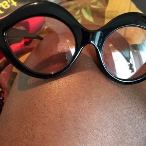Black shades with pinkish lenses cat eye shape.